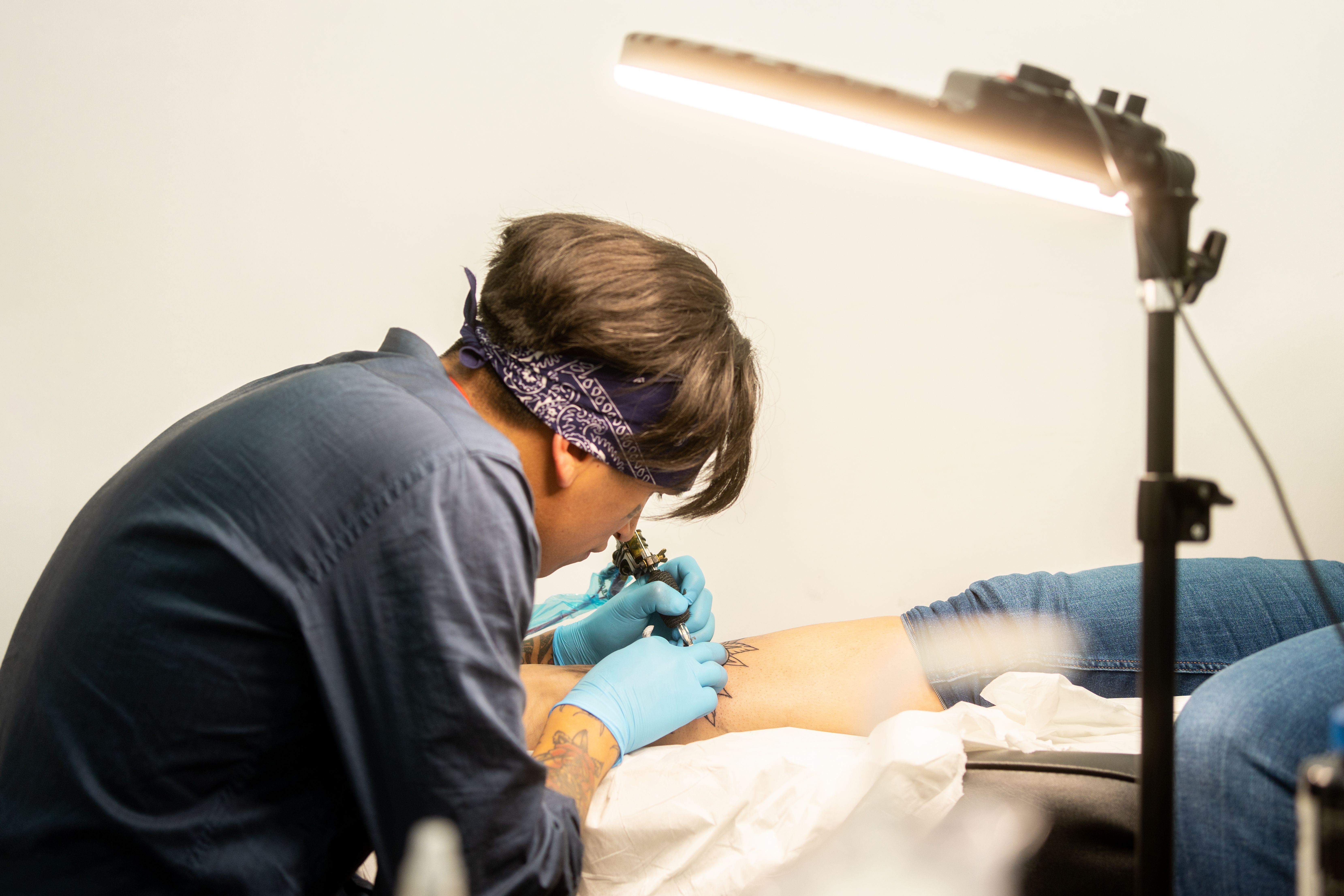 Tattoo artist tattooing leg in a studio