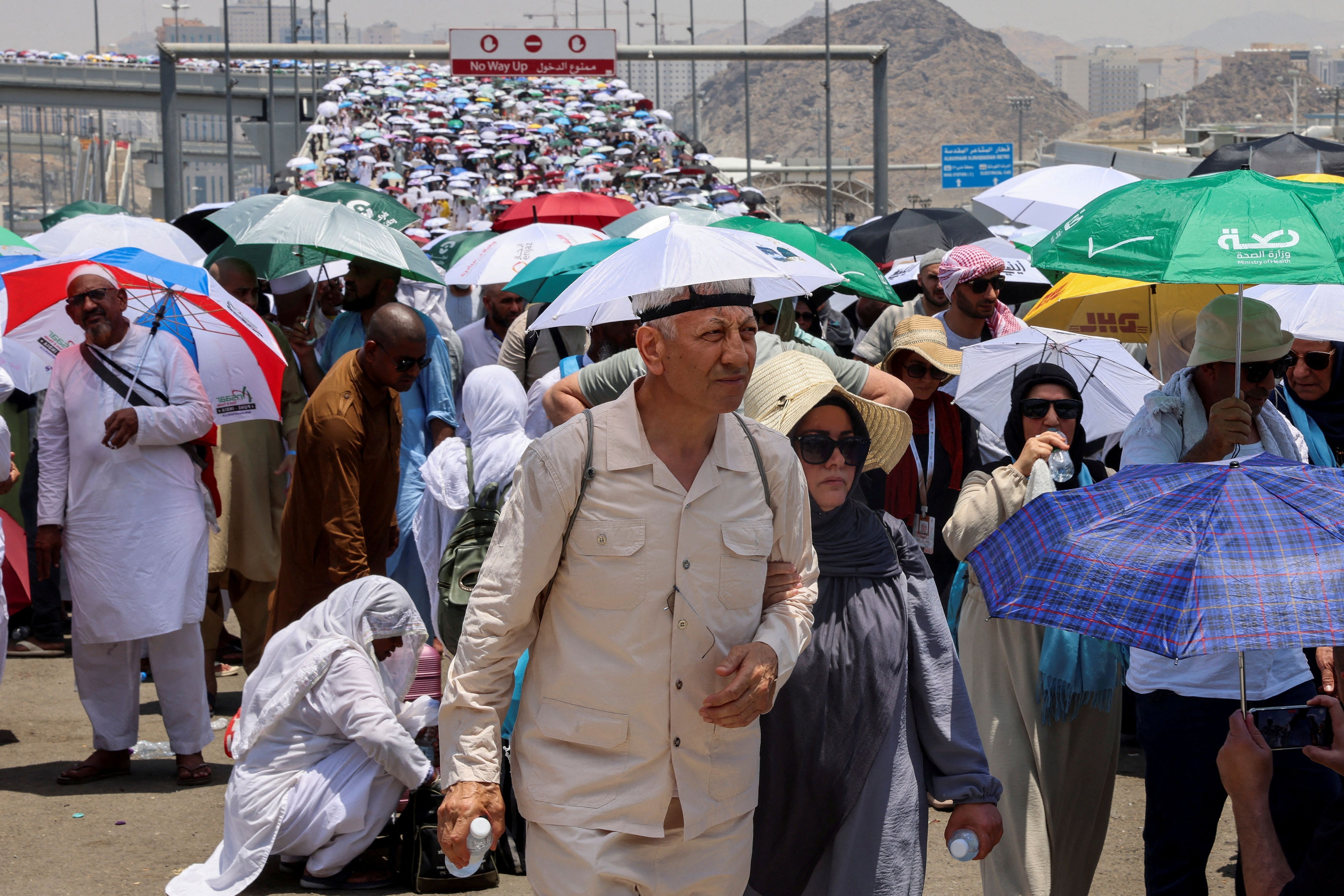 Peregrinos muçulmanos caminham com guarda-chuvas no terceiro dia do ritual de apedrejamento de Satanás, em meio a um clima extremamente quente, durante peregrinação anual do hajj, em Mina, Arábia Saudita