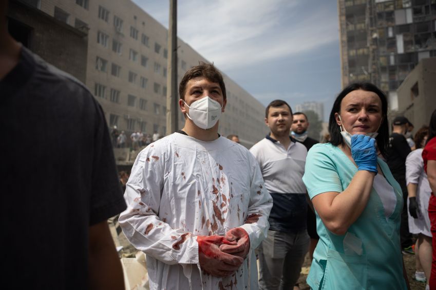 Médico com vestígios de sangue em suas roupas olha para a limpeza de escombros de um prédio em um dos maiores hospitais infantis da Ucrânia, "Okhmatdyt", parcialmente destruído por um ataque de míssil russo em 8 de julho de 2024 em Kiev, na Ucrânia / Oleksandr Magula/Suspilne Ukraine/JSC "UA:PBC"/Global Images Ukraine via Getty Images