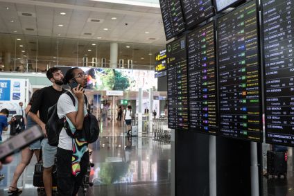 Passageiros olham para uma tela que exibe voos atrasados em meio a falha cibernética global ​​no Aeroporto de Barcelona em 19 de julho de 2024 em Barcelona, ​​​​Espanha.