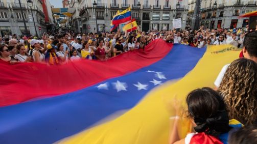 Em Madri, na Espanha, pessoas agitam uma grande bandeira venezuelana durante uma manifestação após eleições