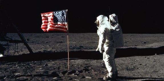 Fotografia de um astronauta ao lado da bandeira dos Estados Unidos durante a missão Apollo 11.