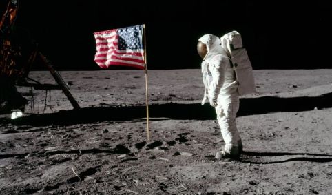 Fotografia de um astronauta ao lado da bandeira dos Estados Unidos durante a missão Apollo 11.