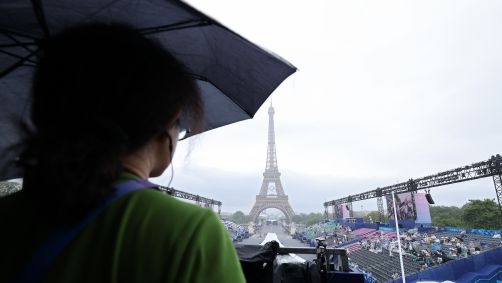 Espectadora com guarda-chuva espera o início da Cerimônia de Abertura dos Jogos Olímpicos