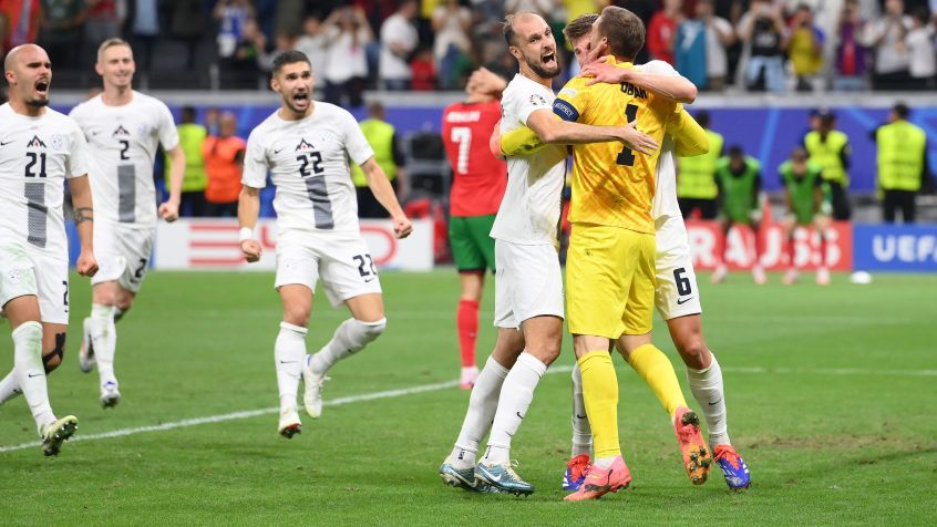 Oblak comemora defesa de pênalti com jogadores da Eslovênia, enquanto Cristiano Ronaldo lamenta ao fundo / Stu Forster/Getty Images