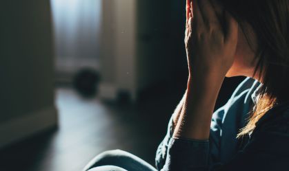 Silhouette of sad and depressed woman sitting on the floor at home
