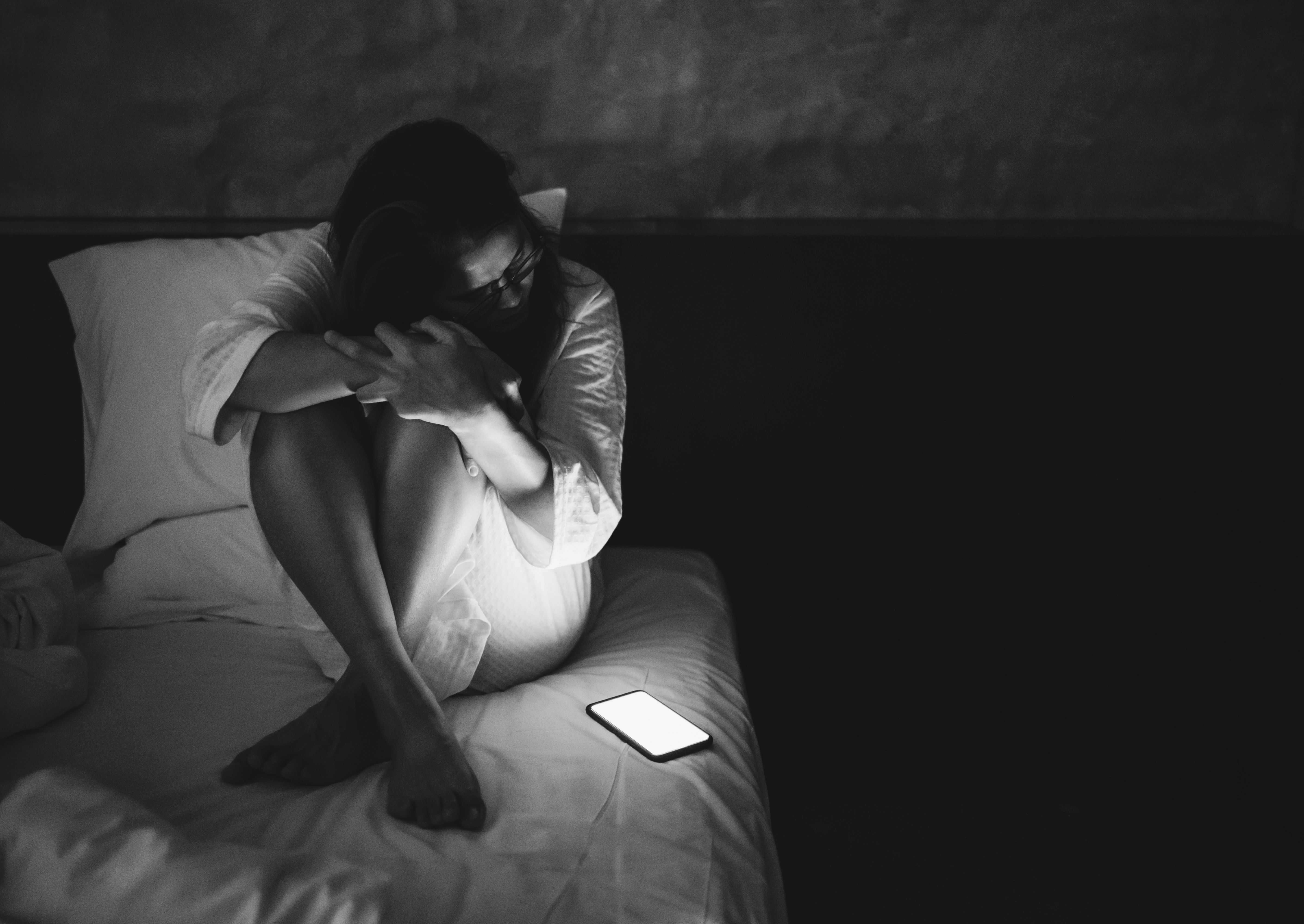 Mulher na cama com celular