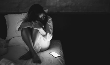 Mulher na cama com celular