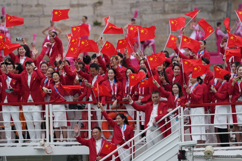 Atletas da equipe da República Popular da China são vistos em um barco ao longo do Rio Sena durante a cerimônia de abertura dos Jogos Olímpicos de Paris 2024 em 26 de julho de 2024 / Aytac Unal/Anadolu via Getty Images