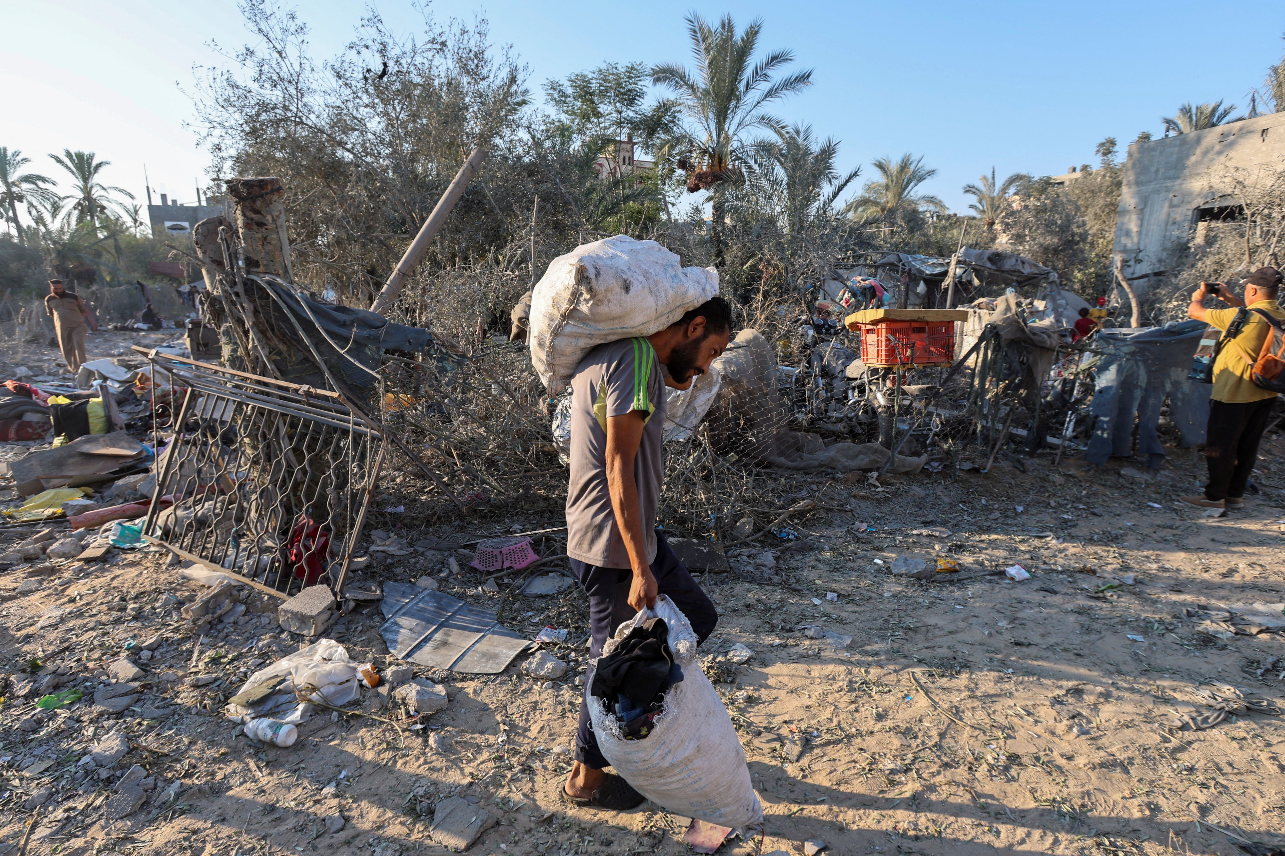 Palestino carrega pertences em local de ataque israelense em Deir Al-Balah, centro de Gaza