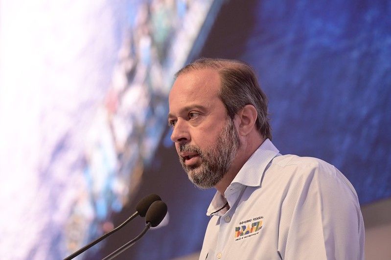 Silveira veste uma camiseta branca e discursa com um microfone. Tem barba e cabelos grisalhos