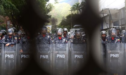 Polícia Nacional Venezuelana vista através de uma barricada montando guarda parando os manifestantes durante o 208º aniversário da declaração de independência da Venezuela em 5 de julho de 2019 em Caracas