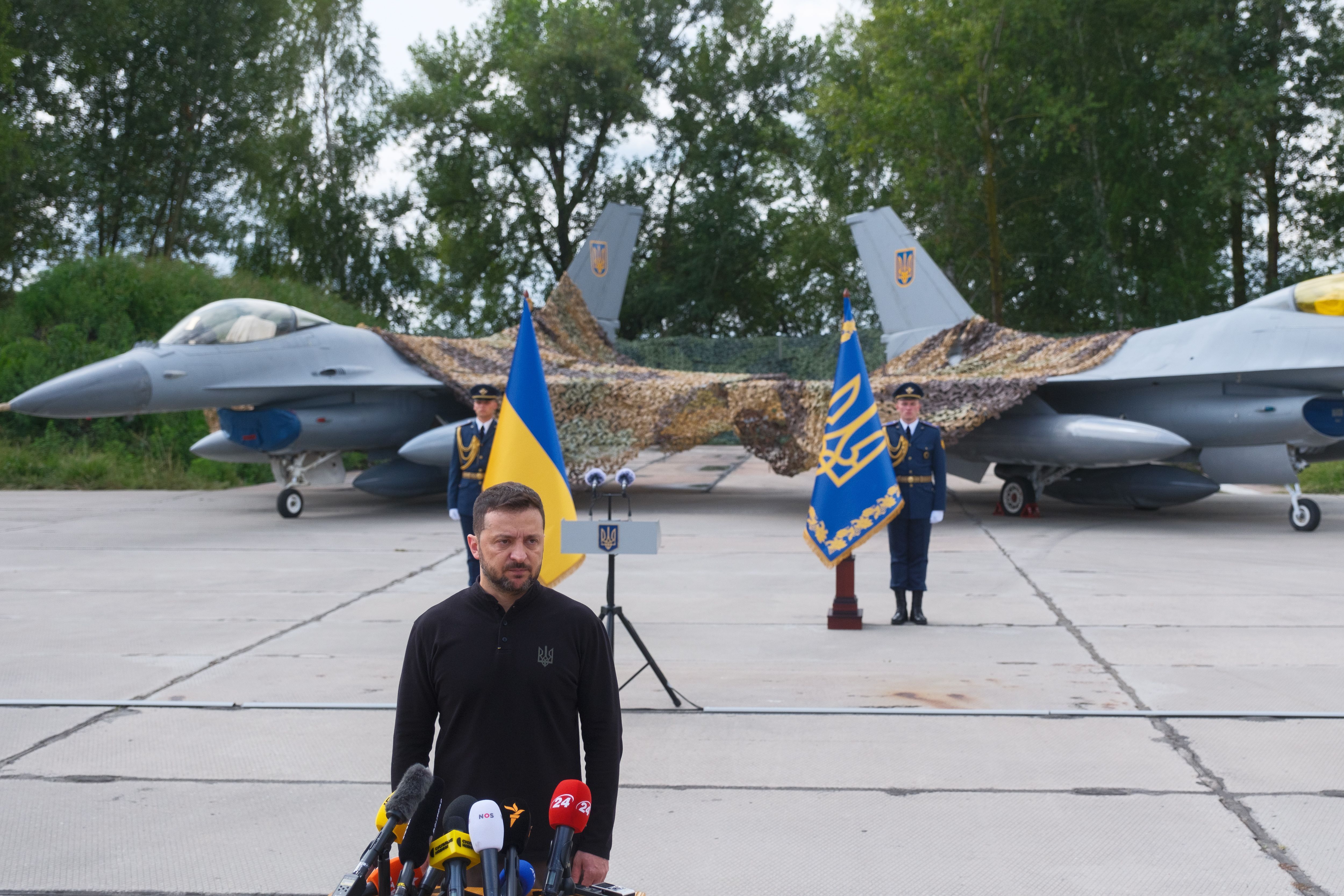 O presidente da Ucrânia Volodymyr Zelenskyi fica em frente aos primeiros General Dynamics F-16 Fighting Falcons recebidos pela Ucrânia enquanto parabeniza os militares ucranianos no Dia da Força Aérea Ucraniana em 4 de agosto de 2024