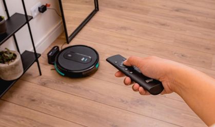 A fotografia apresenta uma pessoa segurando o controle remoto do robô aspirador WAP W400.