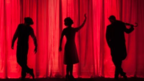 Atores e atrizes encenam peça em palco de teatro