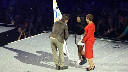 Tom Cruise recebendo a bandeira olímpica de Simone Biles. A ginasta carregou a bandeira durante a execução do hino americano ao lado da prefeita de LA, Karen Bass