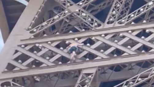Homem escalando a Torre Eiffel no último dia de Olimpíada