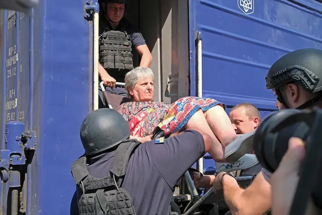Liubov, de 70 anos, é içada para o trem de evacuação pela polícia de Pokrovsk • Ivana Kottasová/CNN