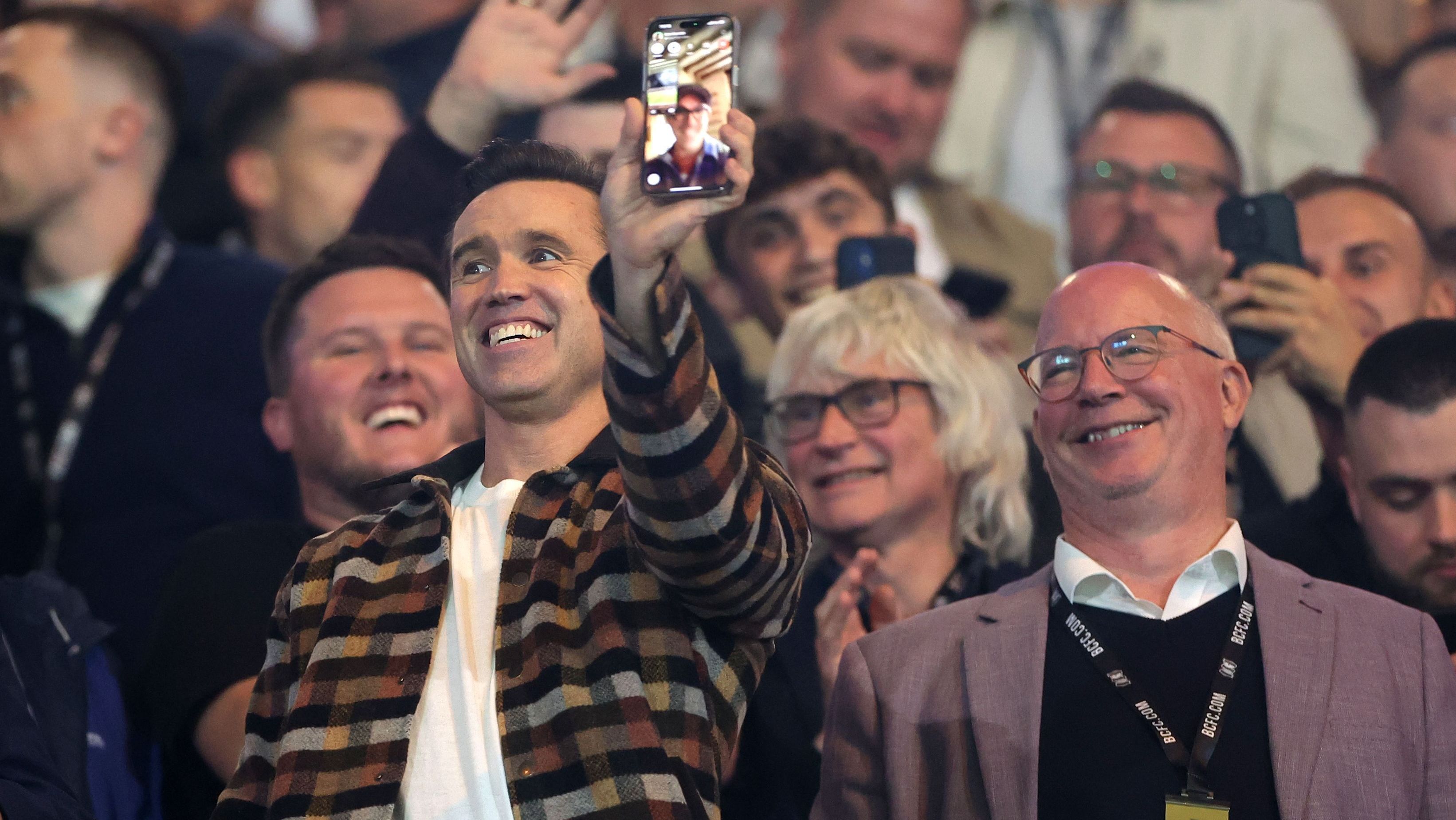 Rob McElhenney, co-proprietário do Wrexham, faz chamada de vídeo com o ator Ryan Reynolds, sócio na equipe, durante partida contra o Birmingham • Alex Pantling/Getty Images