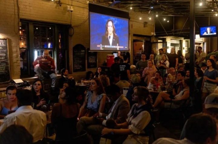 Pessoas assistem ao debate de Kamala Harris e Donald Trump em um pub em Washington, DC. • Tristen Rouse/CNN