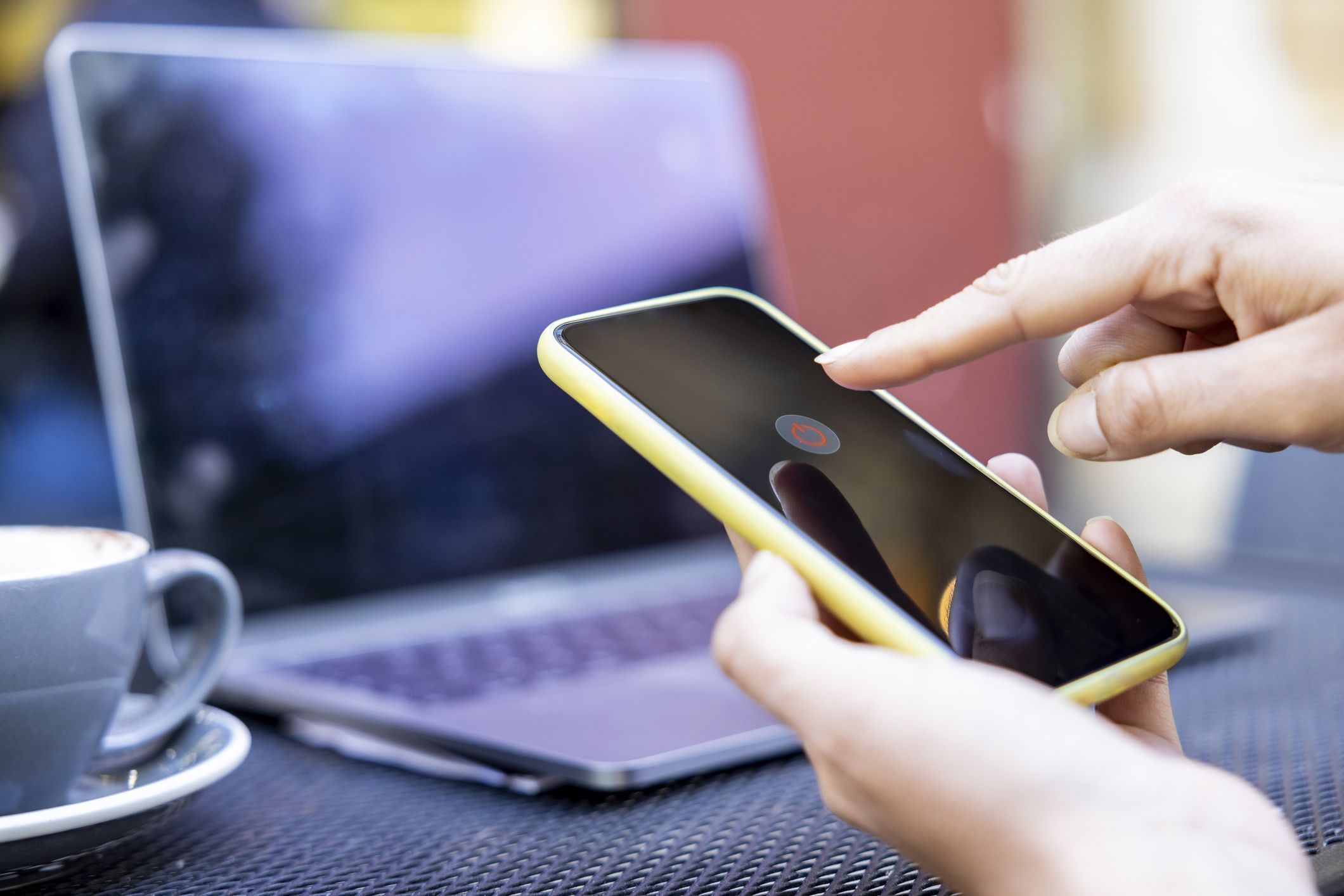 Hands of businesswoman turning off mobile phone at sidewalk cafe