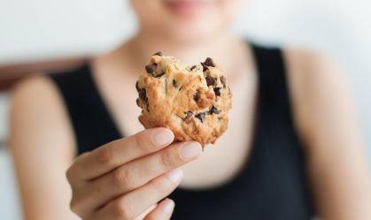A young Southeast Asian woman is holding a freshly baked cookie