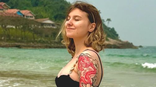 Isabel Veloso está em uma praia e tem um leve sorriso no rosto