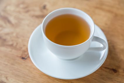 Xícara com chá amarelado em mesa