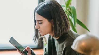 Jovem observa conteúdo no celular