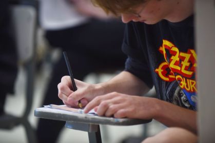 Jovem fazendo um vestibular. Ele está segurando um lápis preto