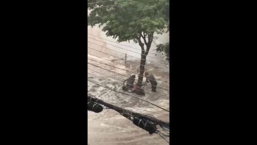 Homens seguram moto que seria levada pela enxurrada na região do Morumbi, na zona sul de São Paulo
