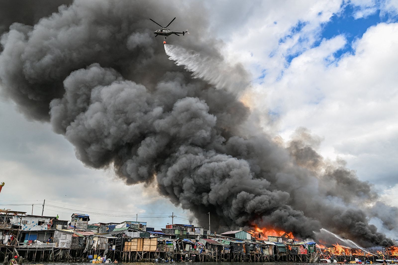 Helicóptero da Força Aérea Filipina joga água sobre favelas em chamas em Tondo, Manila