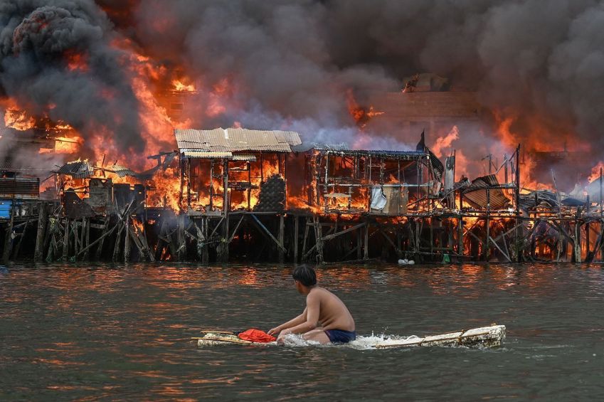 Homem observa casas pegando fogo em Tondo, em Manila, em 24 de novembro de 2024 • Jam Sta Rosa/AFP/Getty Images via CNN Newsource 25 Nov 24