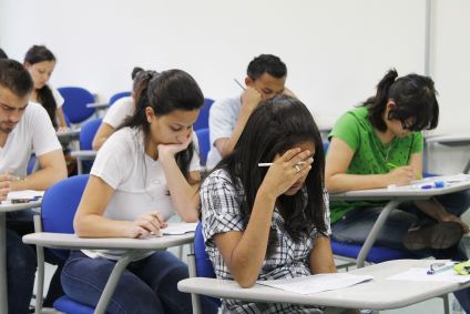 A imagem mostra uma sala de aula com estudantes fazendo uma prova de vestibular