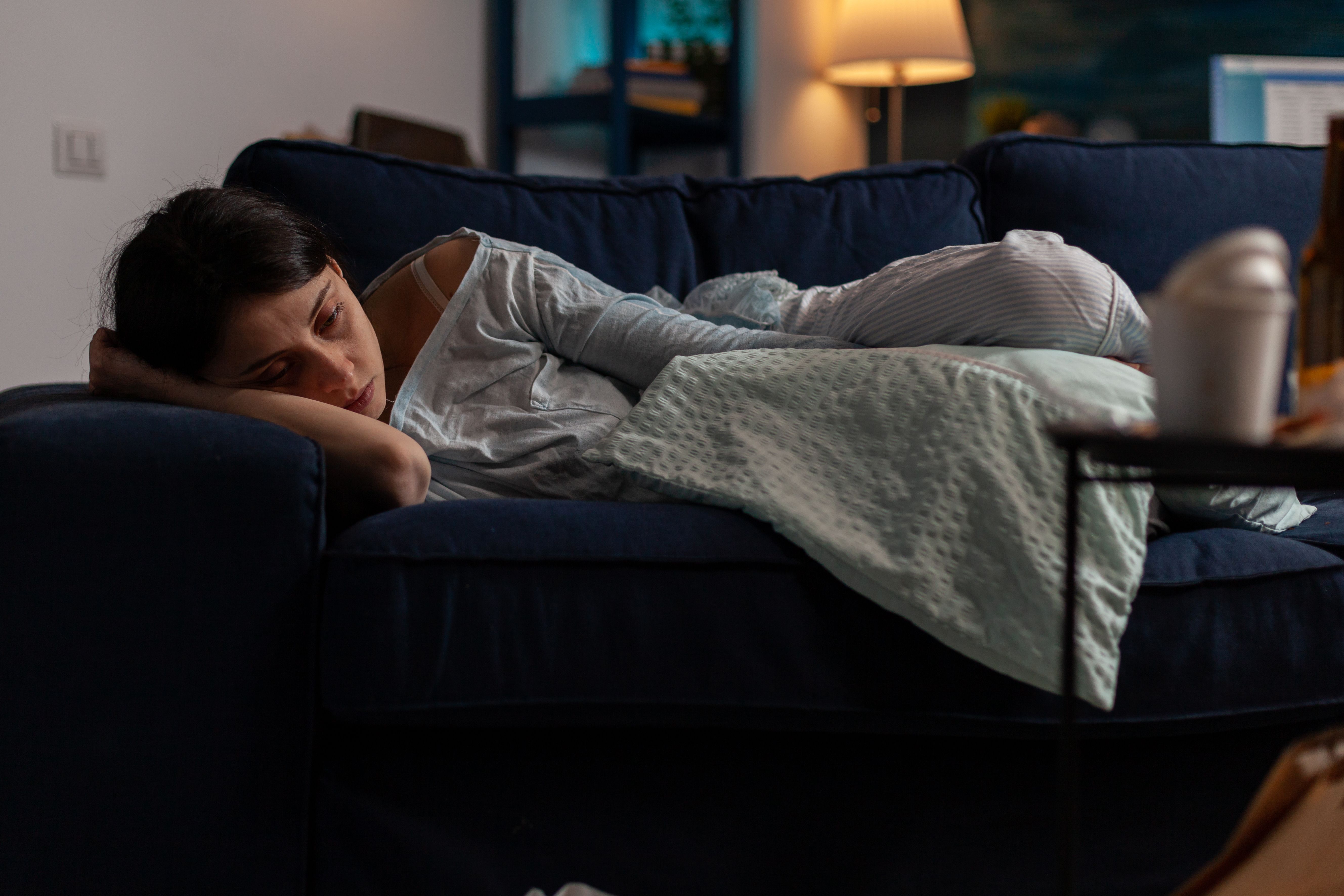 Sad depressed woman with anxiety laying on sofa in solitude