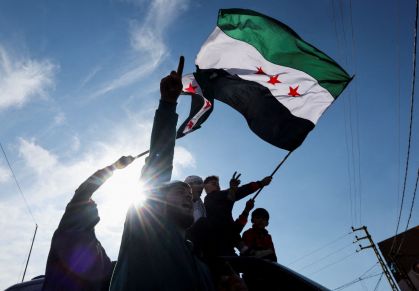 Uma pessoa ergue a bandeira da oposição Síria depois que rebeldes anunciaram que depuseram o presidente Bashar al-Assad, no Líbano, em 8 de dezembro de 2024.