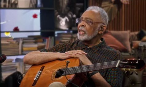 O cantor Gilberto Gil. Ele segura um violão no colo.