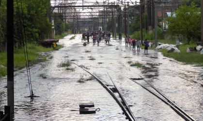 Passageiros caminham pelos trilhos após alagamento na região da estação Brás, em São Paulo