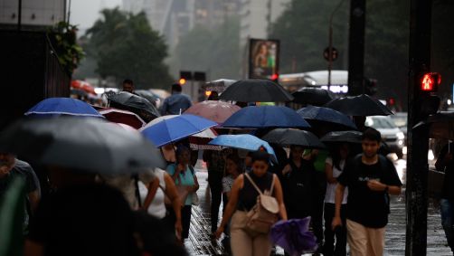 Pedestres se protegem da chuva durante temporal em São Paulo