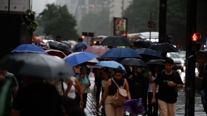 Pedestres se protegem da chuva durante temporal em São Paulo