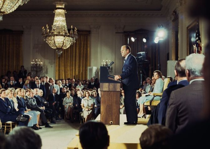Gerald Ford (1913 - 2006) faz discurso após juramento de posse como presidente dos Estados Unidos no Salão Leste da Casa Branca em Washington em 9 de agosto de 1974, com a esposa, Betty (1918 - 2011), sentada no palco • UPI/Bettmann Archive/Getty Images