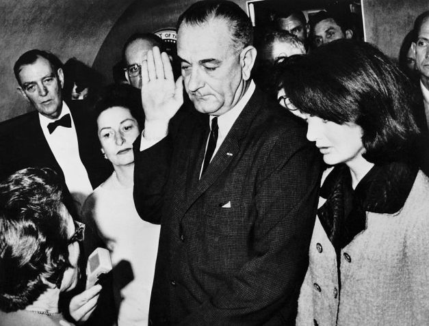 Lyndon B. Johnson durante sua posse imediatamente após o assassinato de John F. Kennedy, com Jackie Kennedy ao seu lado no Air Force One, o avião oficial da Presidência dos EUA • Bettman