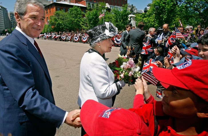 O então presidente George W. Bush e a Rainha Elizabeth II cumprimentam crianças no caminho entre a Casa Branca e a Blair House, em Washington D.C. • Chip Somodevilla/Getty Images