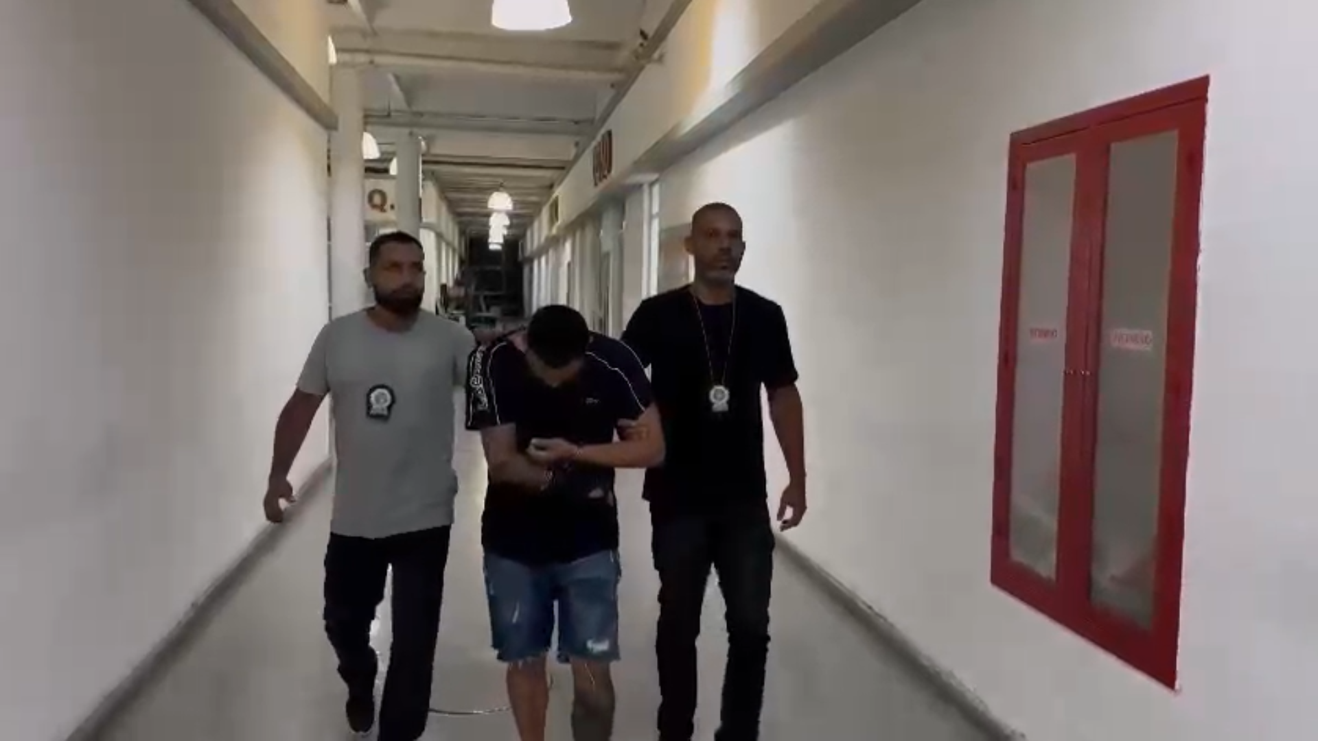 Imagem mostra momento em que homem é conduzido pelos agentes na Cidade de Polícia, no Rio