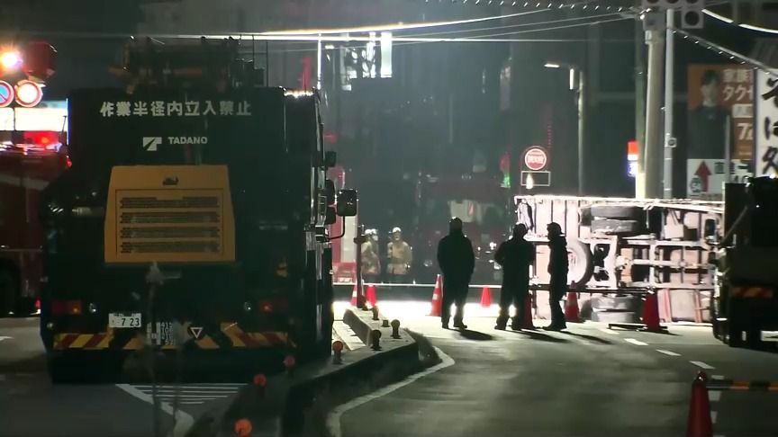 Autoridades ao redor da cratera que engoliu caminhão e motorista em Saitama, Japão. • Reprodução/TV Tokyo