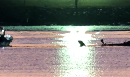 Barco de equipes de resgate próximo a destroços de helicóptero militar após colisão com avião de passageiros nos Estados Unidos