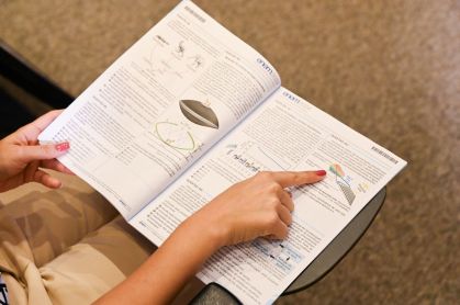Caderno do Enem. Ele está aberto. O dedo de uma pessoa aponta para uma das questões
