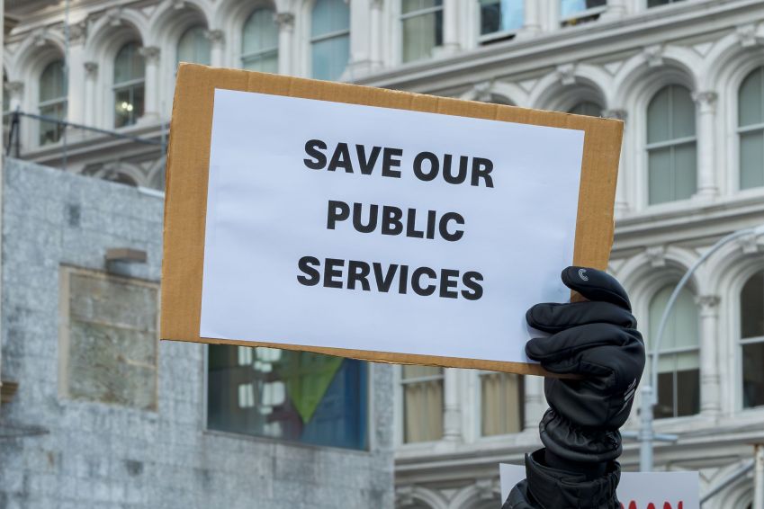 Placa com a frase “Salve nosso Serviço Público”, durante manifestação contra os cortes de funcionários federais nos EUA. • Erik McGregor/LightRocket via Getty Images