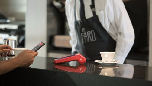 Consumidor utiliza o celular para realizar pagamento em maquininha da Getnet