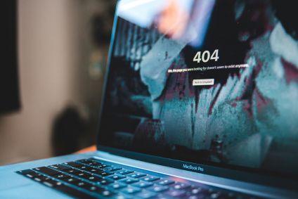 A fotografia apresenta a frente da tela de um MacBook, da Apple, com uma página escrita "erro 404".